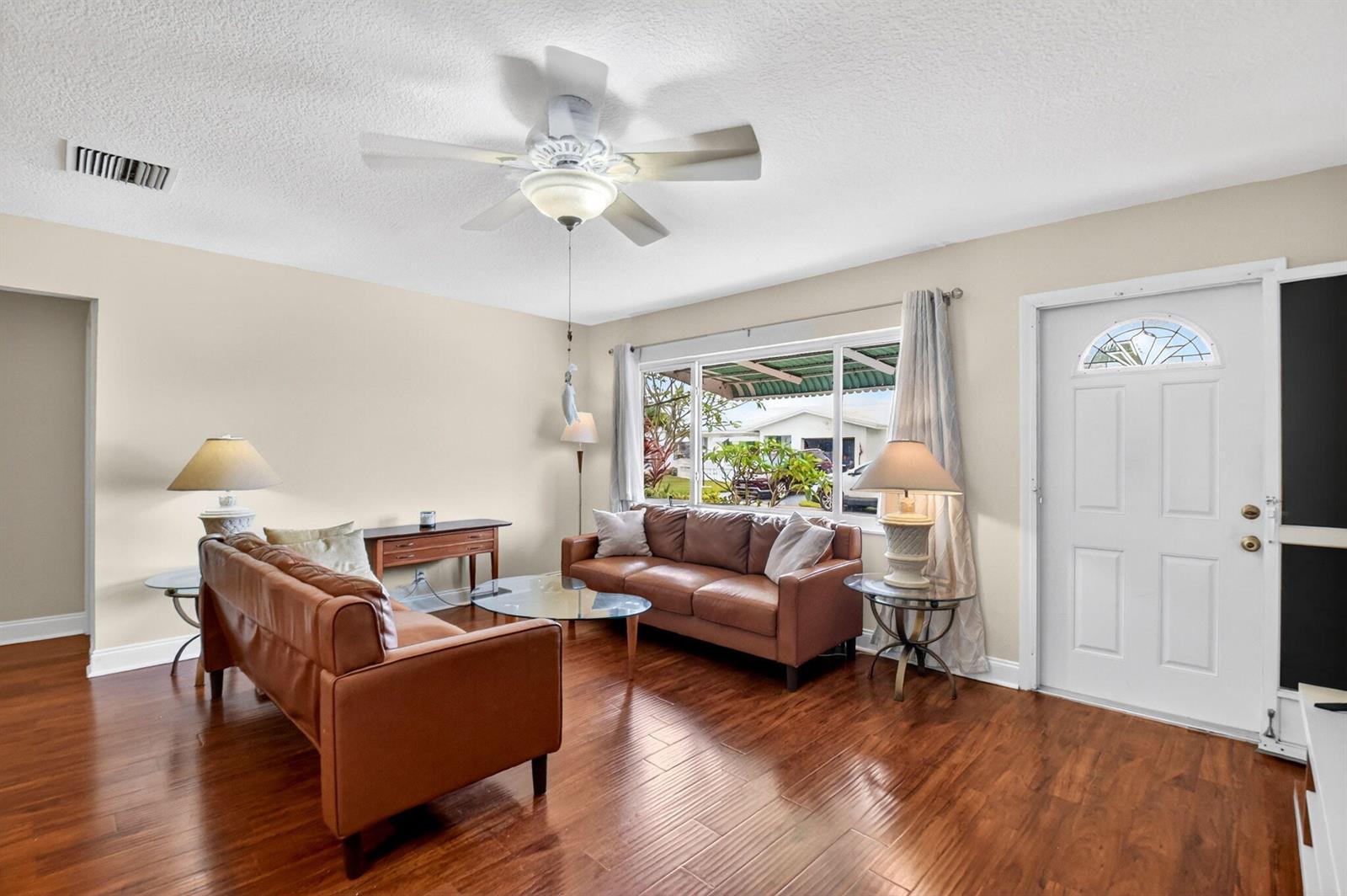 A living room features brown leather sofas, a glass coffee table, and hardwood flooring — 112 SW 9th Street, Boynton Beach FL 33426, BOYNTON BEACH, FL