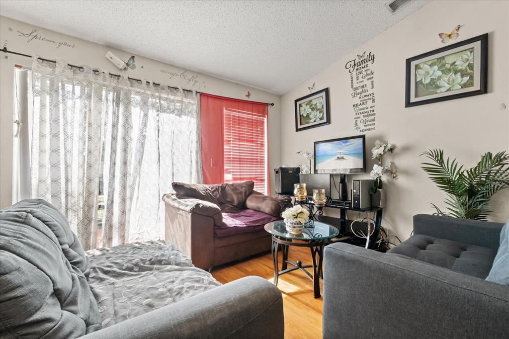 A living room features two gray sofas, a brown armchair, and a television on a stand — 1321 DUNBARTON COURT, KISSIMMEE, FL