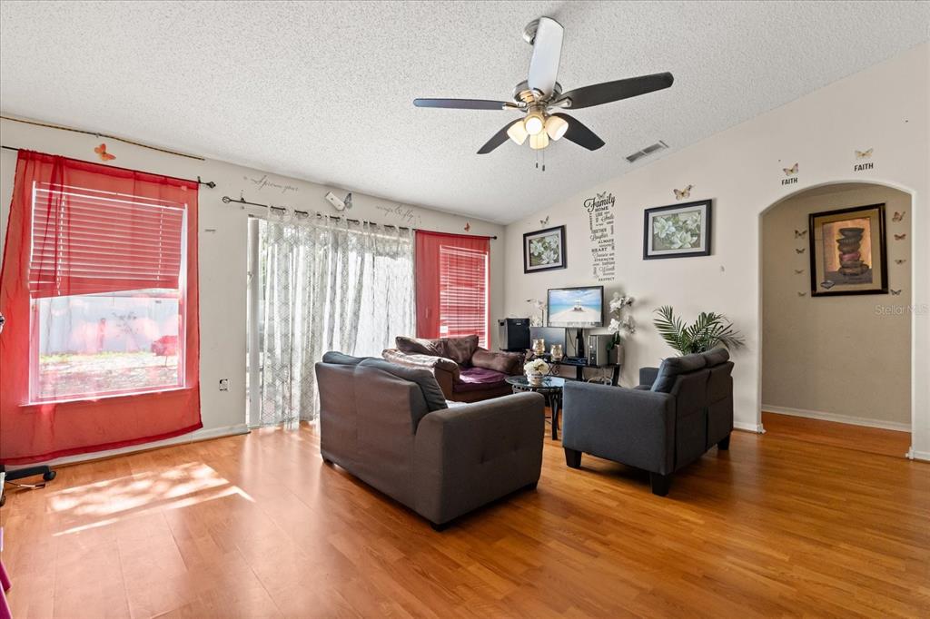 A living room features hardwood floors, a ceiling fan, and two gray sofas — 1321 DUNBARTON COURT, KISSIMMEE, FL