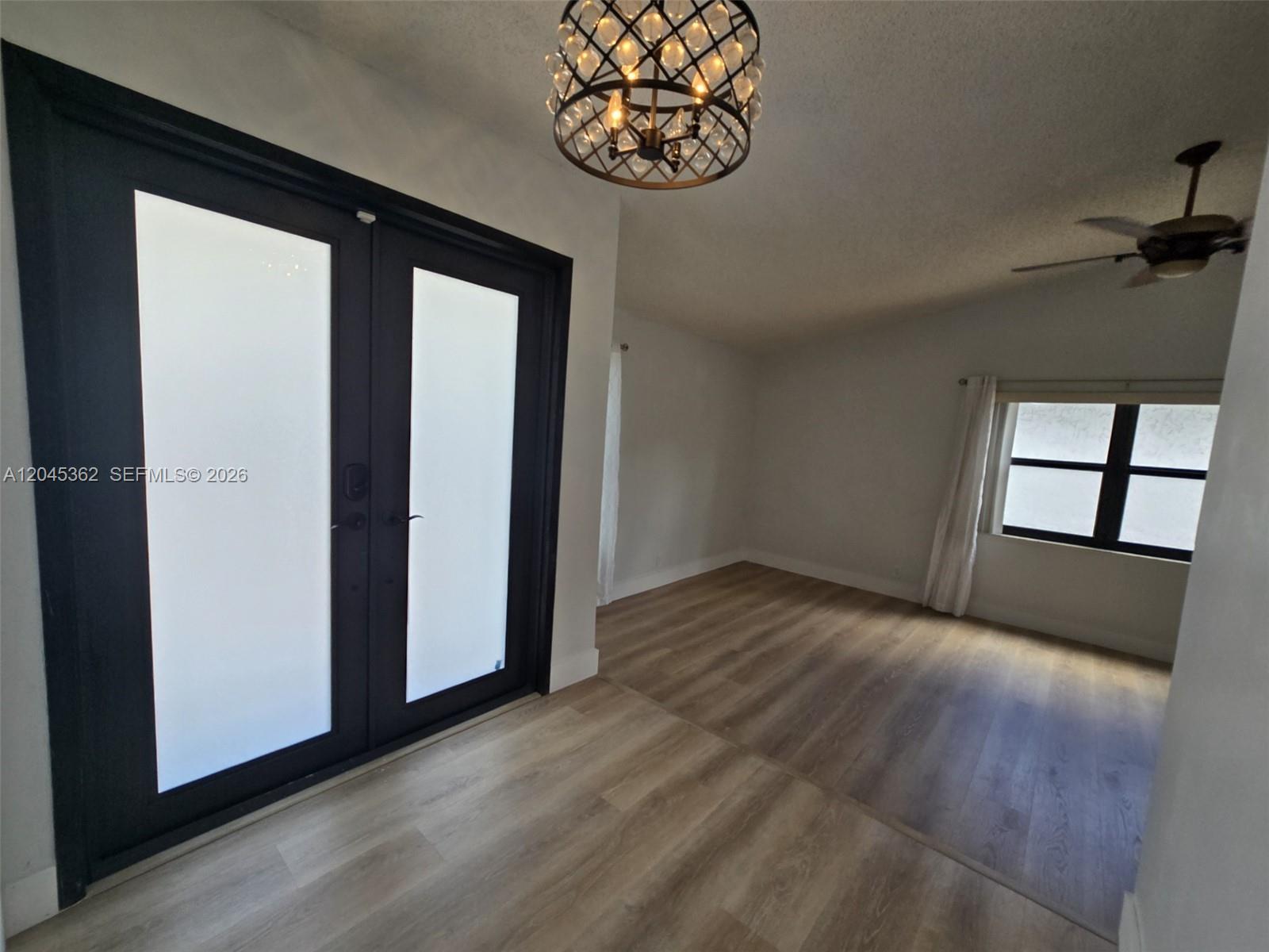 An entryway with a dark-framed double door, a decorative chandelier, and light wood flooring — 740 SW 99th Ct Cir # 0, Miami FL 33174, MIAMI, FL