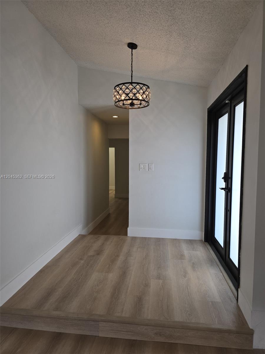 An entryway features a raised wooden floor, a modern drum pendant light, and black-framed doors — 740 SW 99th Ct Cir # 0, Miami FL 33174, MIAMI, FL