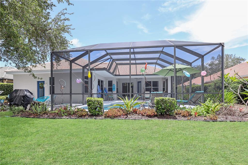 A backyard view of a house with a screened-in pool and patio area — 956 SCHERER WAY, OSPREY, FL