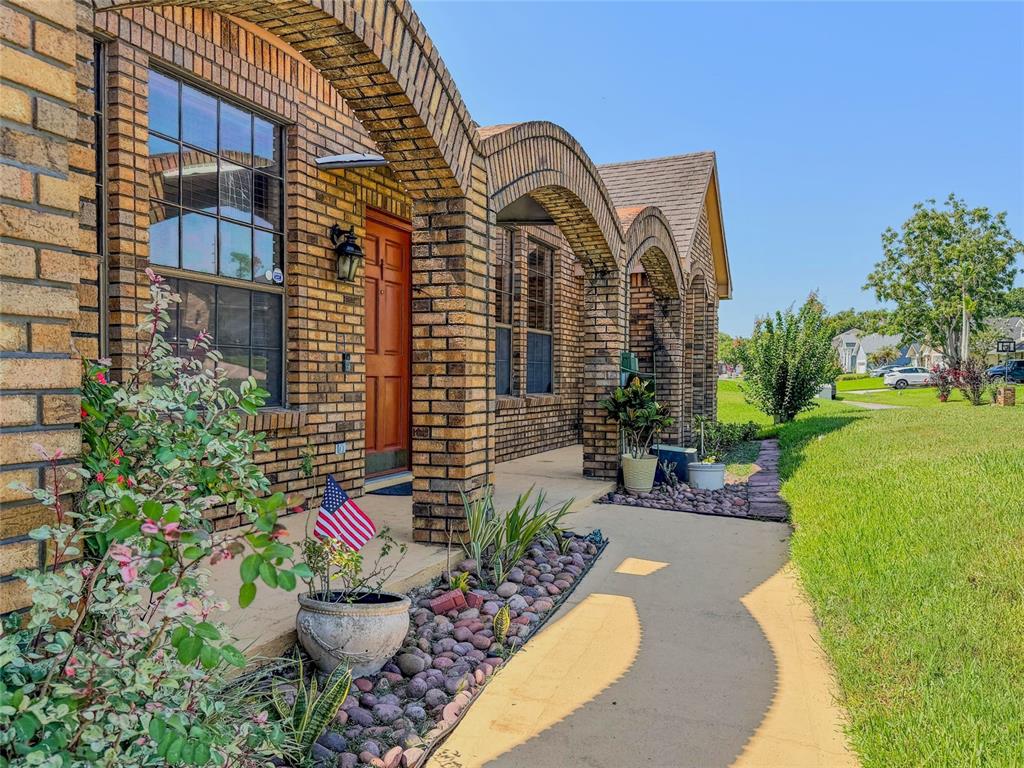 A brick house exterior features a covered porch with arched columns and a concrete walkway — 9731 SIBLEY CIRCLE, ORLANDO, FL