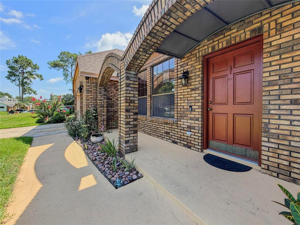 A brick house exterior features a covered entryway with an arched porch and red door — 9731 SIBLEY CIRCLE, ORLANDO, FL