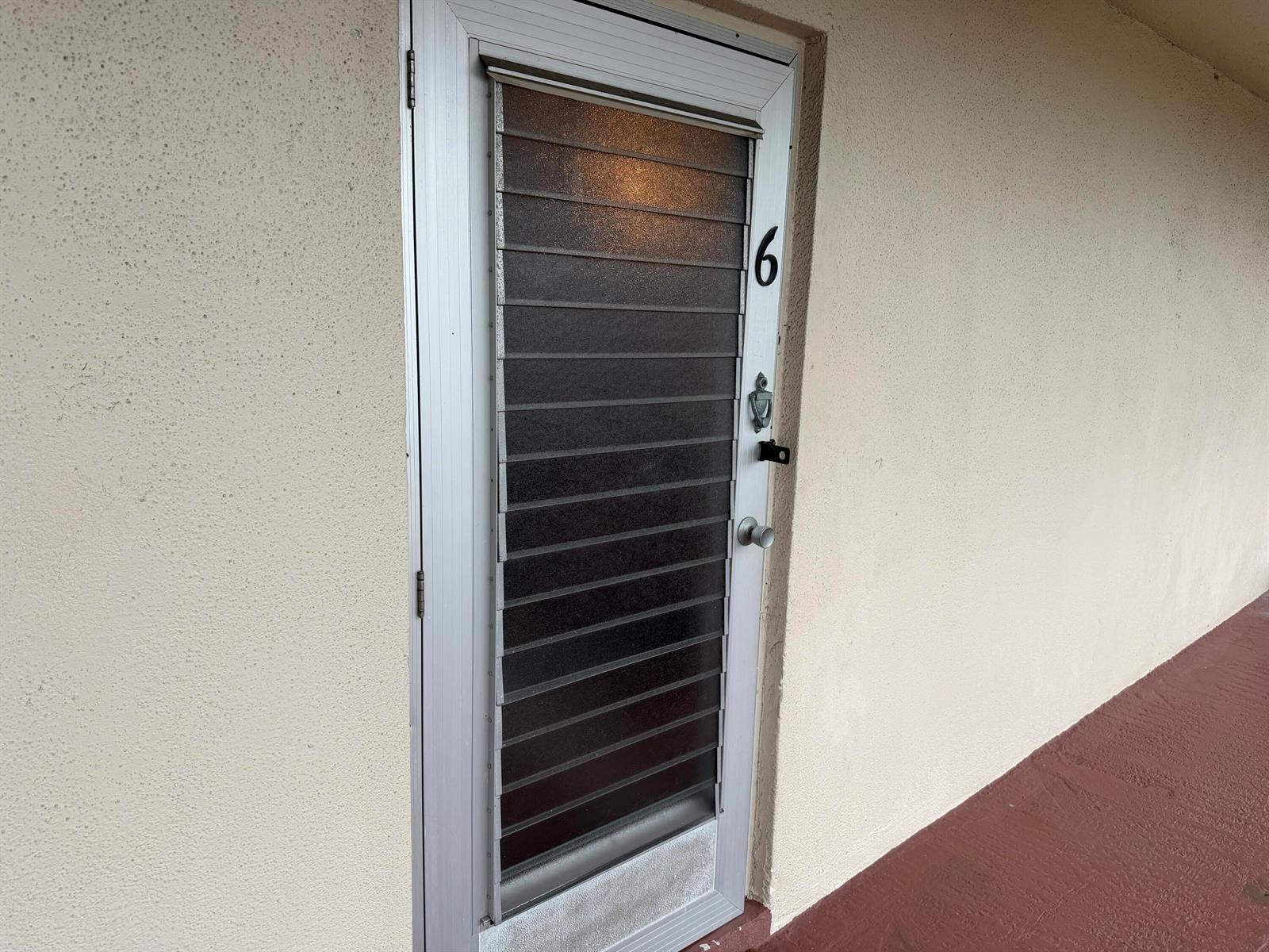 A single exterior door with horizontal glass louvers and the number six is set in a stucco wall — 502 Davis Road # 6, Palm Springs FL 33461, PALM SPRINGS, FL