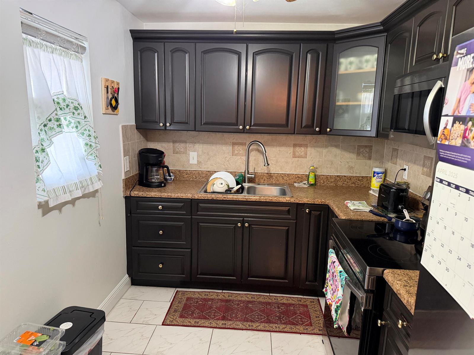 A kitchen features dark wood cabinets, granite countertops, a stainless steel sink, and tile flooring — 502 Davis Road # 6, Palm Springs FL 33461, PALM SPRINGS, FL