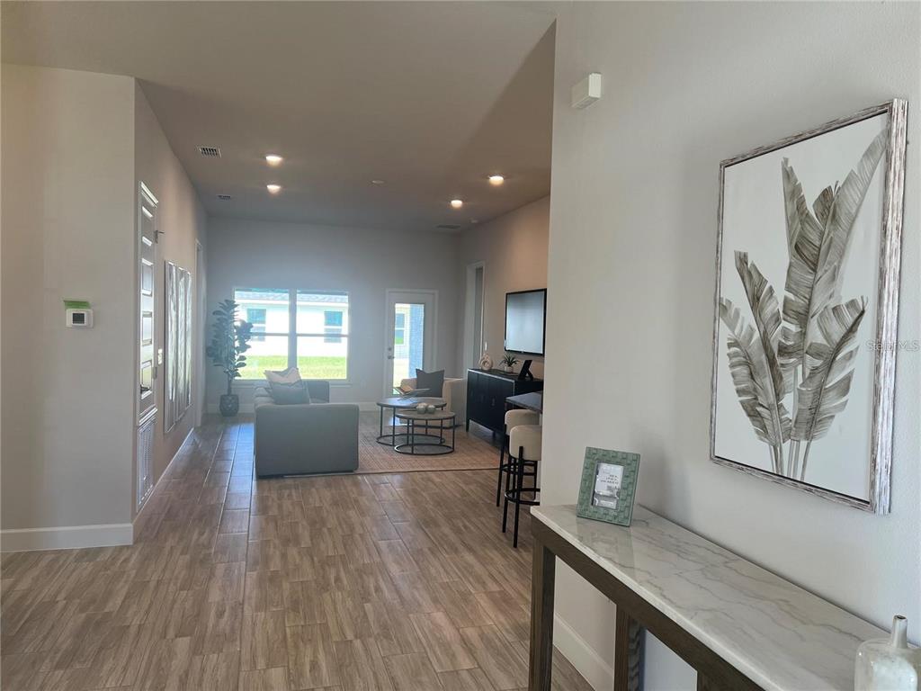 A view from a hallway looking into a living room with tile floors and furniture — 12909 OGDEN GLADE RD STREET, DADE CITY, FL