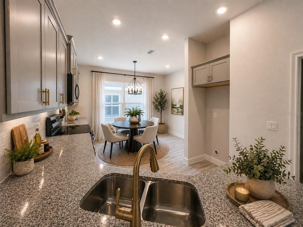 A kitchen with granite countertops and gray cabinets overlooks a dining area with a chandelier — 12909 OGDEN GLADE RD STREET, DADE CITY, FL