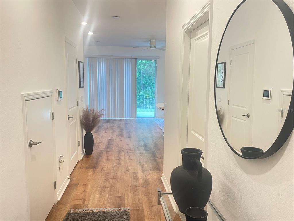 A hallway with wood-look flooring leads toward a living area with sliding glass doors — 3575 DAVENPORT CREEK COURT, KISSIMMEE, FL