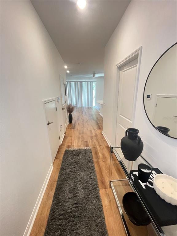 A hallway with wood-look flooring leads toward a bright living area with sliding glass doors — 3575 DAVENPORT CREEK COURT, KISSIMMEE, FL
