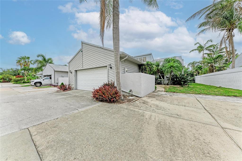 A single-story house with a white garage, concrete driveway, and palm trees under a sky — 11207 LONGWOOD CT, BRADENTON, FL