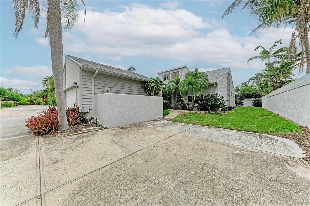 A gray house with a concrete driveway, palm trees, and a low stucco wall — 11207 LONGWOOD CT, BRADENTON, FL