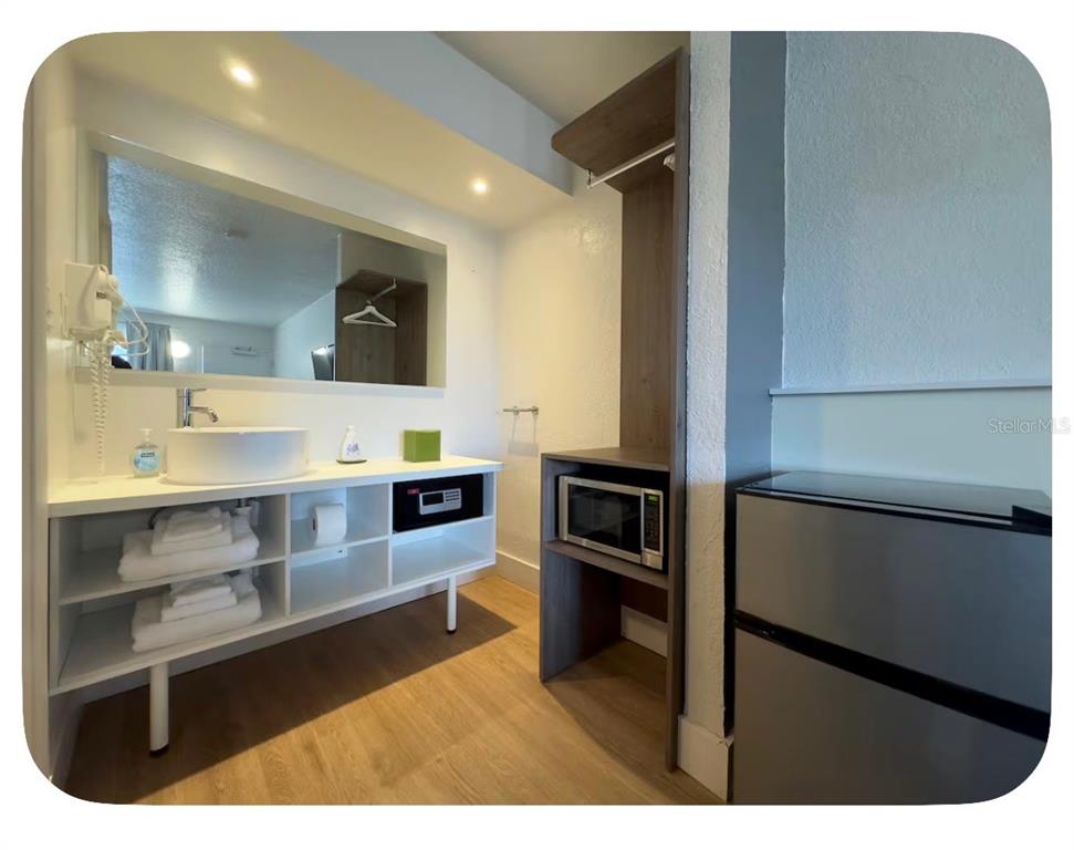 A hotel bathroom vanity area features a vessel sink, microwave, mini-fridge, and open shelving — 5367 W IRLO BRONSON MEMORIAL HIGHWAY UNIT 1-206, KISSIMMEE, FL