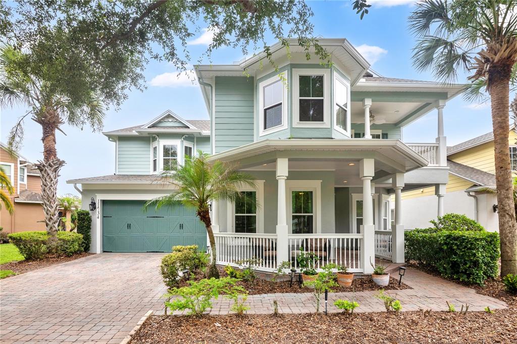 A two-story light green house with a front porch, garage, and palm trees — 11734 ALDENDALE STREET, ORLANDO, FL