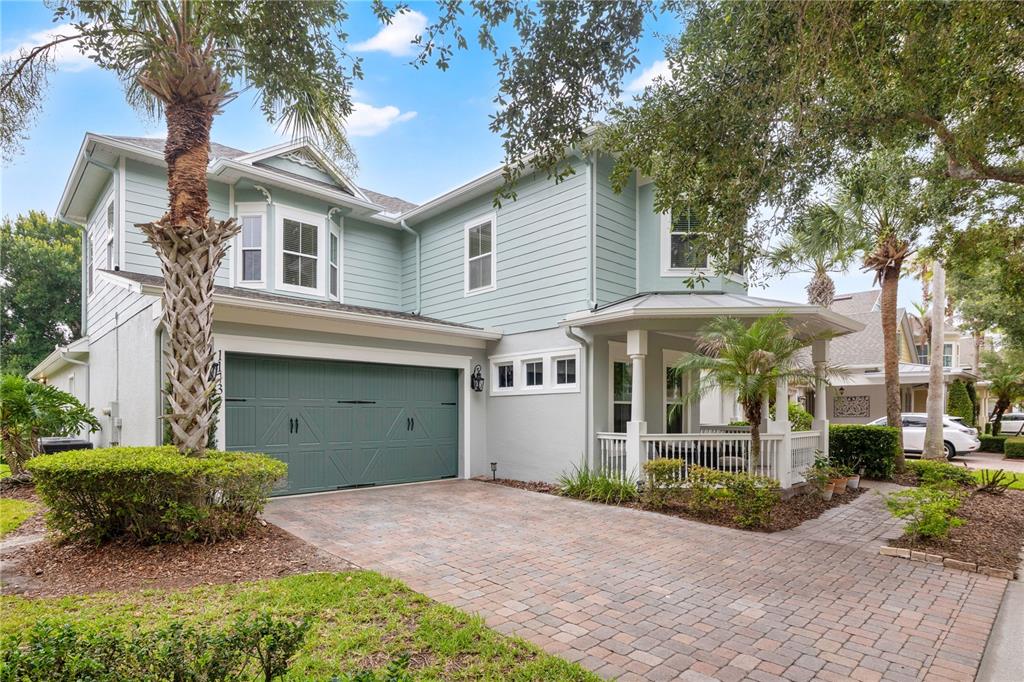 A two-story house with light blue siding, a green garage door, and a front porch — 11734 ALDENDALE STREET, ORLANDO, FL