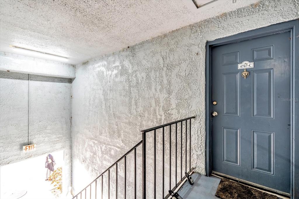 A blue door with a brass knocker sits at the top of a concrete staircase — 4767 S TEXAS AVENUE UNIT 4767C, ORLANDO, FL