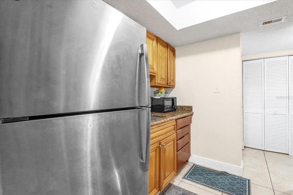 A stainless steel refrigerator stands next to wooden cabinets and a microwave in a kitchen — 4767 S TEXAS AVENUE UNIT 4767C, ORLANDO, FL