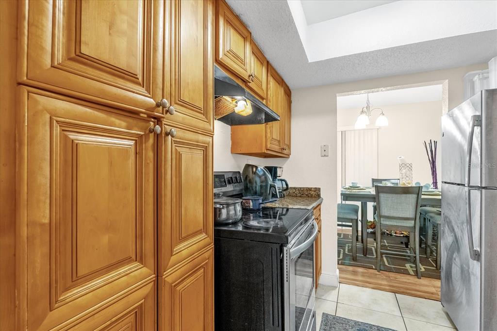 A kitchen features wood cabinets, a black stove, and a stainless steel refrigerator — 4767 S TEXAS AVENUE UNIT 4767C, ORLANDO, FL