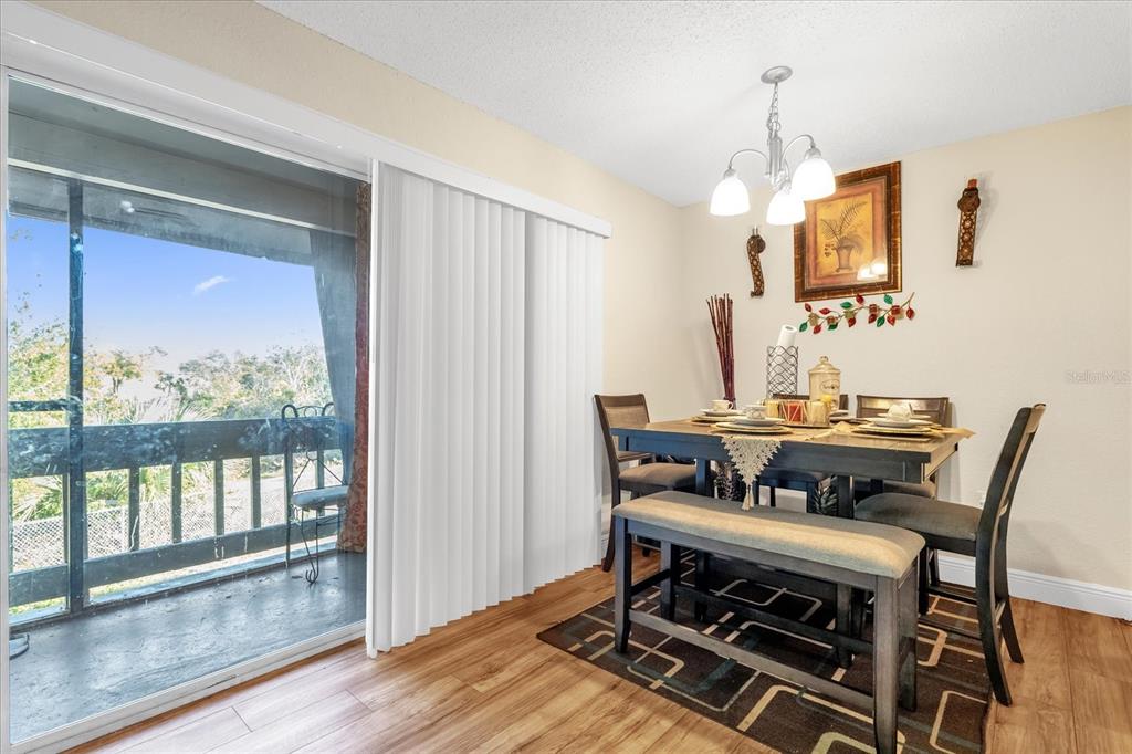 A dining room with wood flooring, a table set for four, and a sliding glass door — 4767 S TEXAS AVENUE UNIT 4767C, ORLANDO, FL
