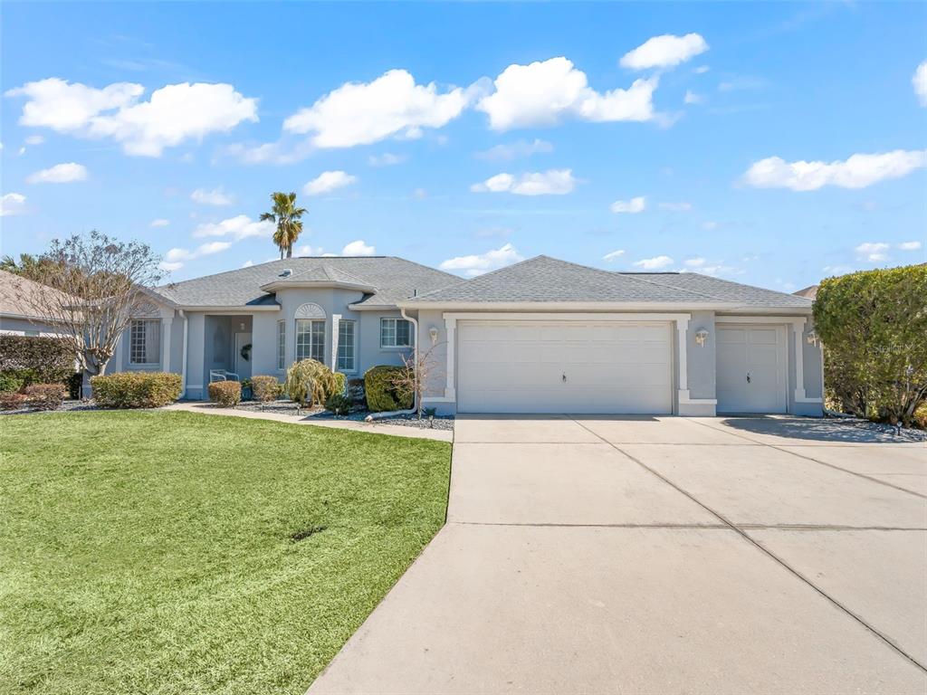 A single-story house with a gray exterior, a three-car garage, and a large concrete driveway — 2449 NW 59TH TERRACE, OCALA, FL