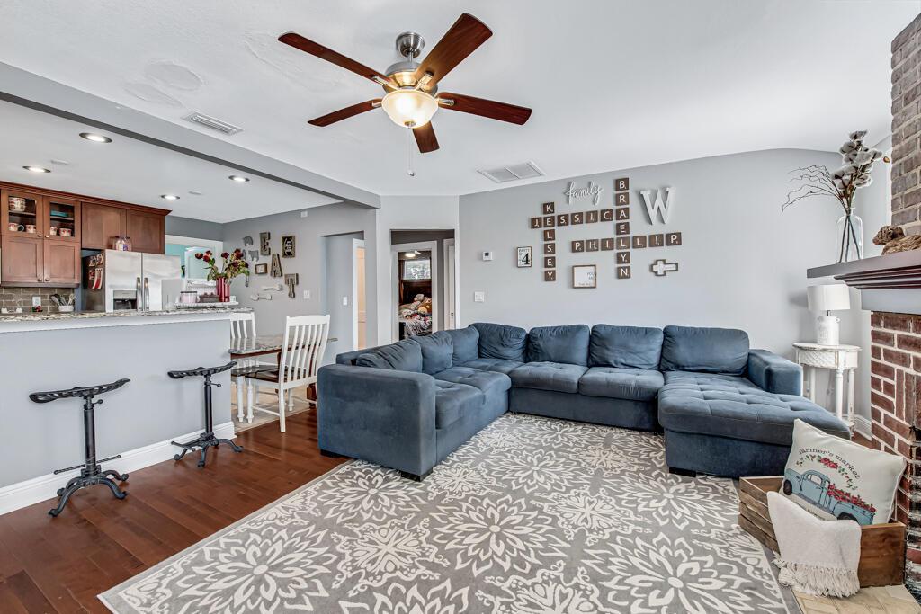 A living room with a blue sectional sofa, patterned rug, and a wall-mounted Scrabble-style display — 416 Deane Duff Street, Clewiston FL 33440, CLEWISTON, FL