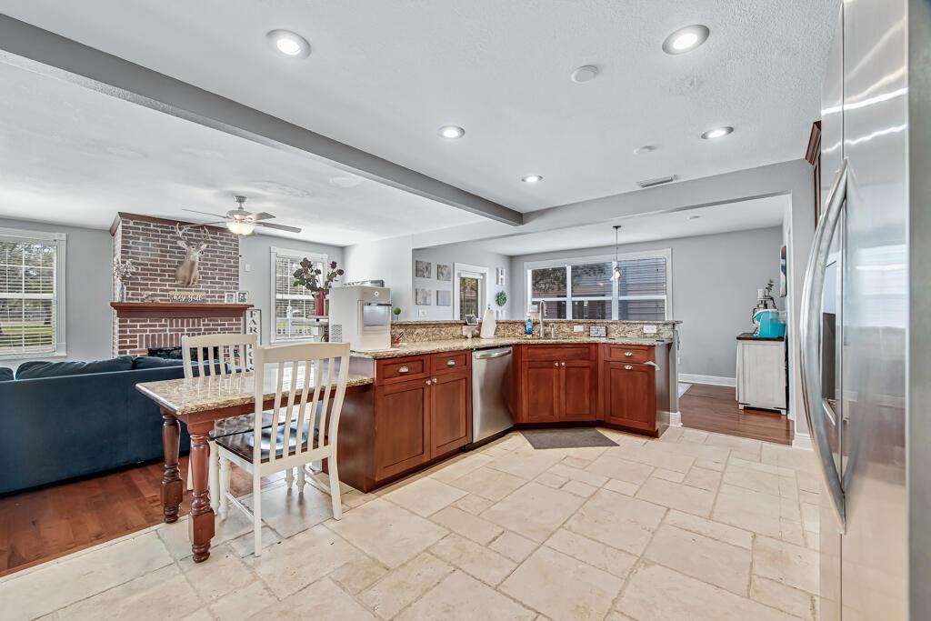 A kitchen with wood cabinets and granite countertops opens to a living room with a fireplace — 416 Deane Duff Street, Clewiston FL 33440, CLEWISTON, FL