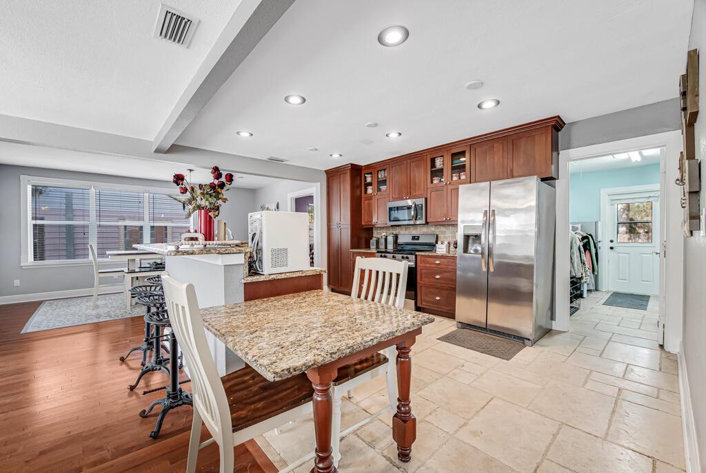 A kitchen features wooden cabinets, granite countertops, stainless steel appliances, and a dining area — 416 Deane Duff Street, Clewiston FL 33440, CLEWISTON, FL