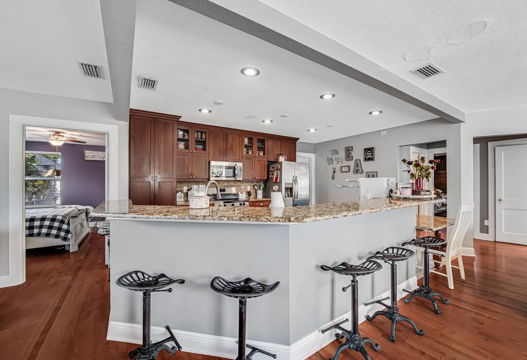 A kitchen with dark wood cabinets, granite countertops, and a breakfast bar with metal stools — 416 Deane Duff Street, Clewiston FL 33440, CLEWISTON, FL