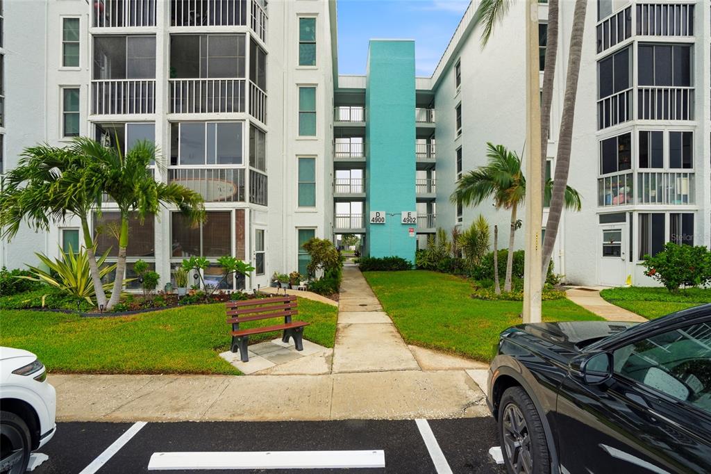 An exterior view of two multi-story apartment buildings with a central walkway and palm trees — 4900 38TH WAY S UNIT 404, ST PETERSBURG, FL
