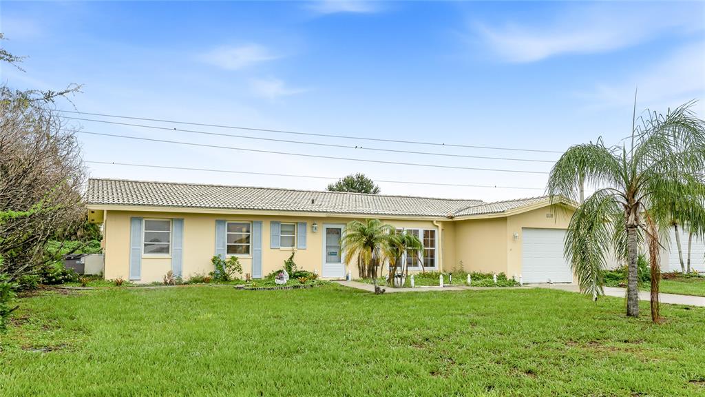 A single-story house with a light yellow exterior, a tiled roof, and a front lawn — 113 ANNAPOLIS LANE, ROTONDA WEST, FL