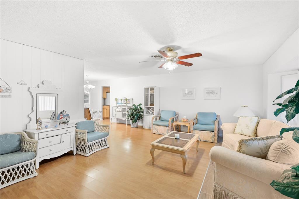 A bright living room features light wood flooring, white walls, and a ceiling fan — 113 ANNAPOLIS LANE, ROTONDA WEST, FL