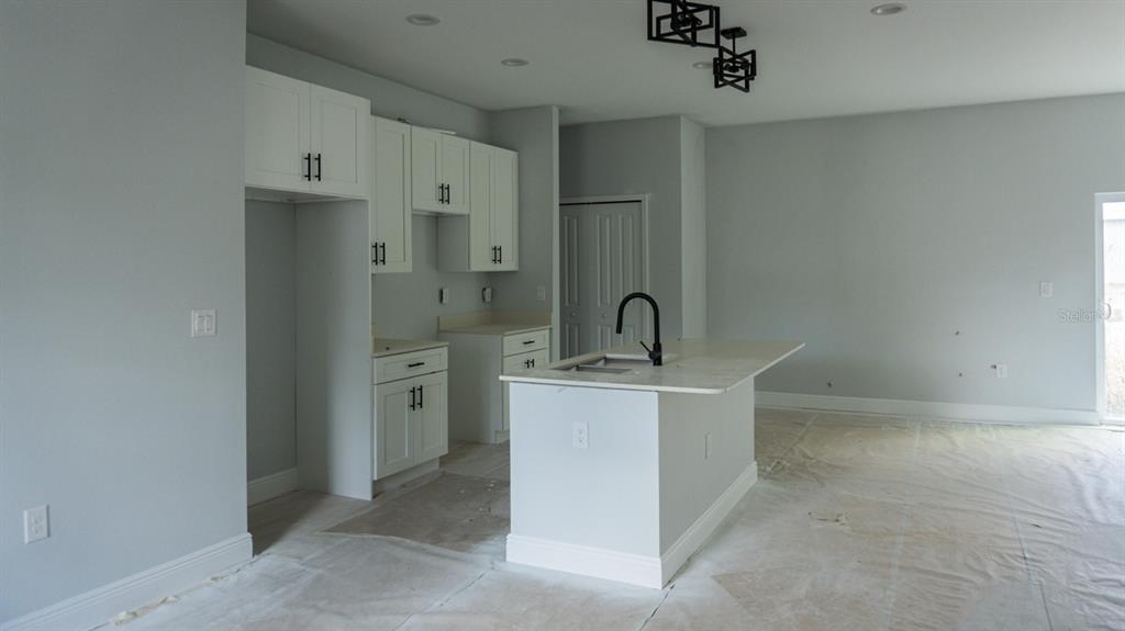 A kitchen features white cabinets, a central island with a sink, and light-colored walls — 105 PONOKA STREET, PORT CHARLOTTE, FL