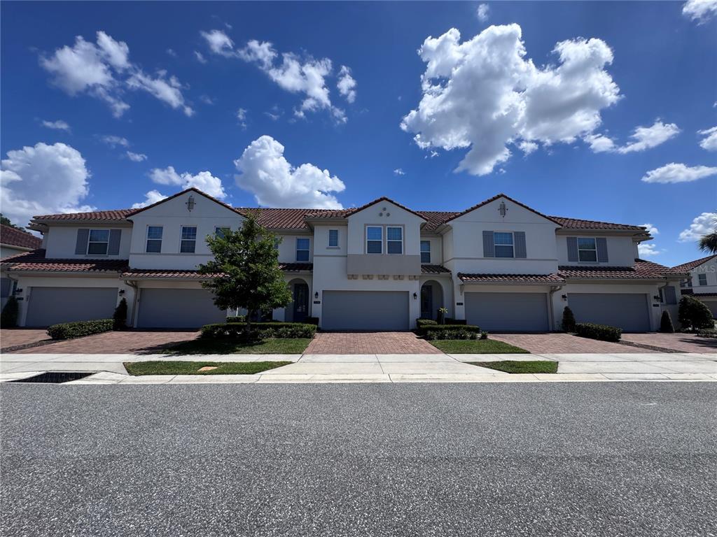 A multi-unit residential building with a tile roof, stucco exterior, and attached garages — 2518 CAGLIARI LANE, APOPKA, FL