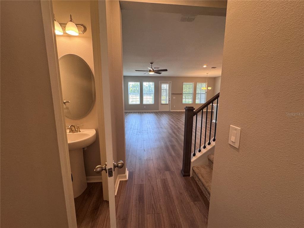 A view from a hallway into a living area with wood-look flooring and stairs — 2518 CAGLIARI LANE, APOPKA, FL