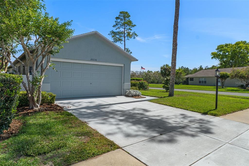 A light blue house with a two-car garage and a concrete driveway under a blue sky — 18236 WEBSTER GROVE DRIVE, HUDSON, FL