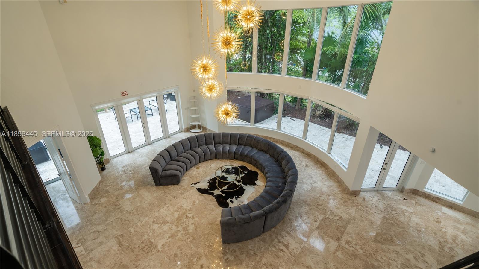 A high-ceilinged living room features a large curved sofa, marble flooring, and floor-to-ceiling windows — 112 NW 14th Way, Dania Beach FL 33004, DANIA BEACH, FL