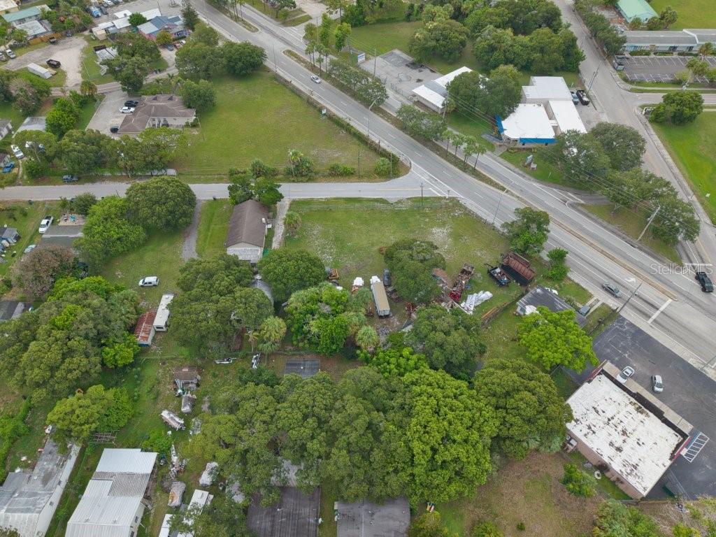 An aerial view shows a grassy lot with trees, a small building, and nearby roads — 2108 OKEECHOBEE ROAD, FORT PIERCE, FL