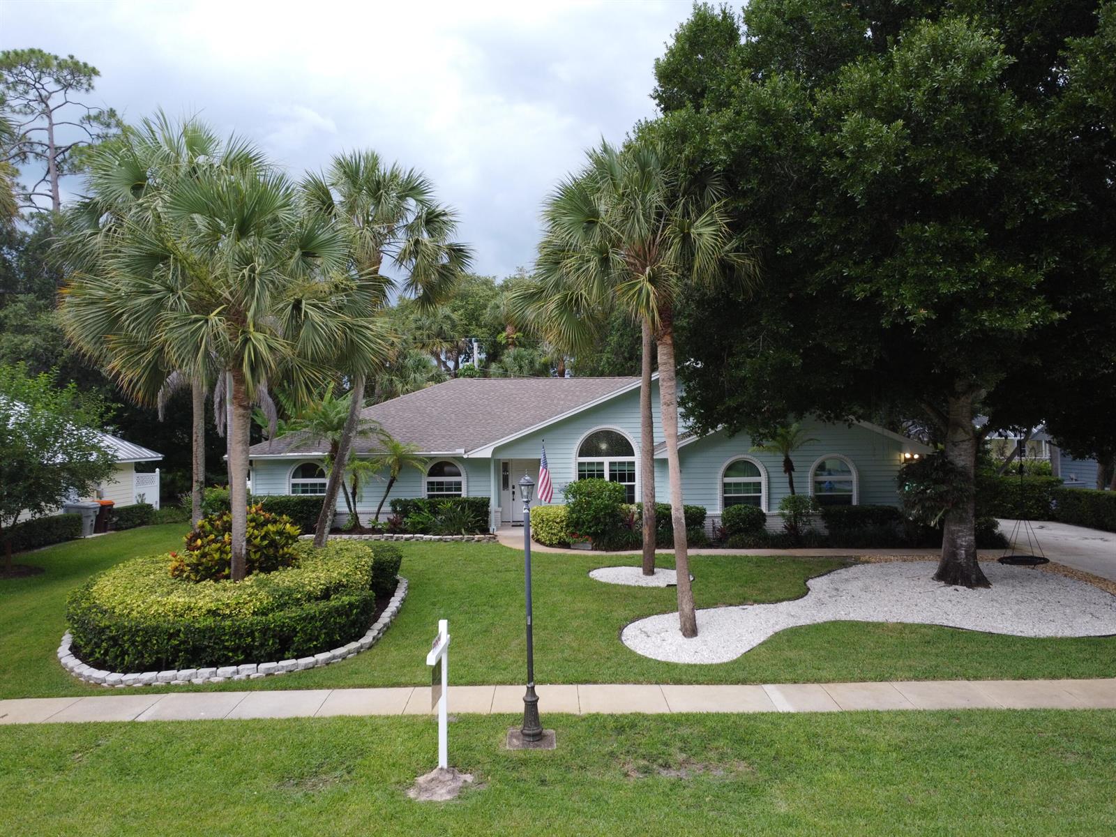 A light green single-story house with palm trees and a landscaped front yard — 129 38th Court, Vero Beach FL 32968, VERO BEACH, FL