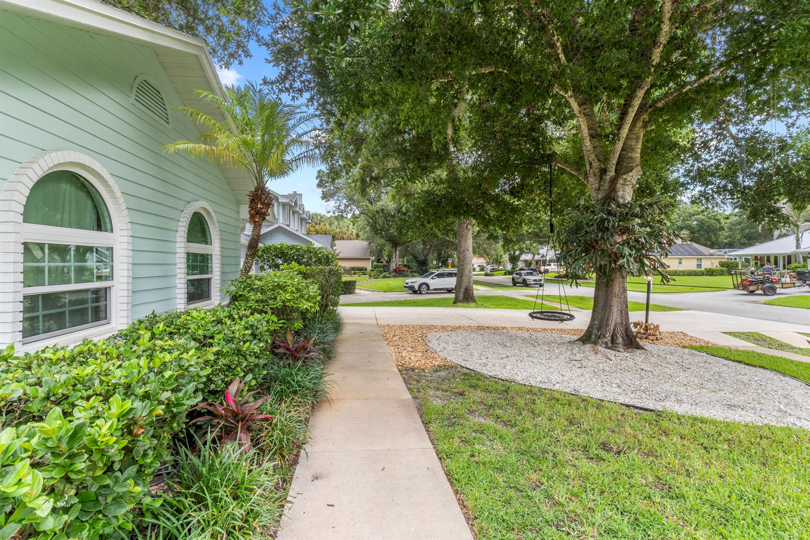 A light green house exterior features a sidewalk, a large tree with a swing, and landscaping — 129 38th Court, Vero Beach FL 32968, VERO BEACH, FL