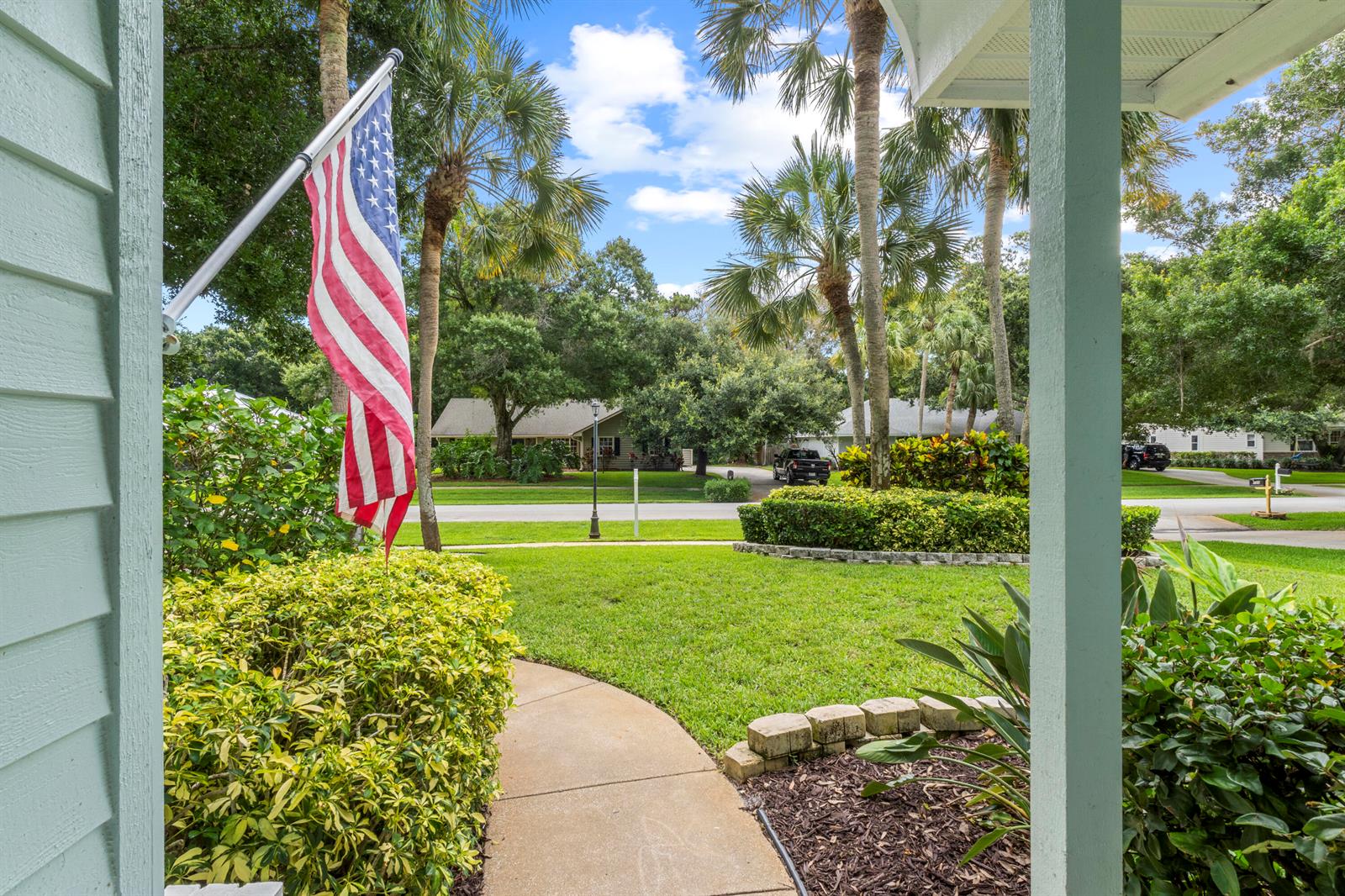 A view from a porch looking out at a front yard with palm trees — 129 38th Court, Vero Beach FL 32968, VERO BEACH, FL