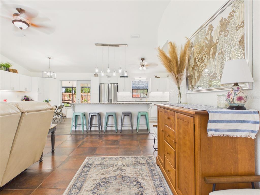 An open-concept kitchen features a white island with teal stools and a wooden sideboard — 14700 SE 94TH AVENUE, SUMMERFIELD, FL