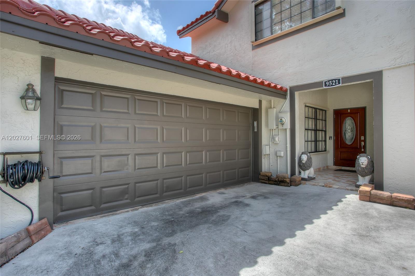 A two-story house exterior features a brown garage door, a tiled roof, and two lion statues — 9521 NW 18th Mnr, Plantation FL 33322, PLANTATION, FL