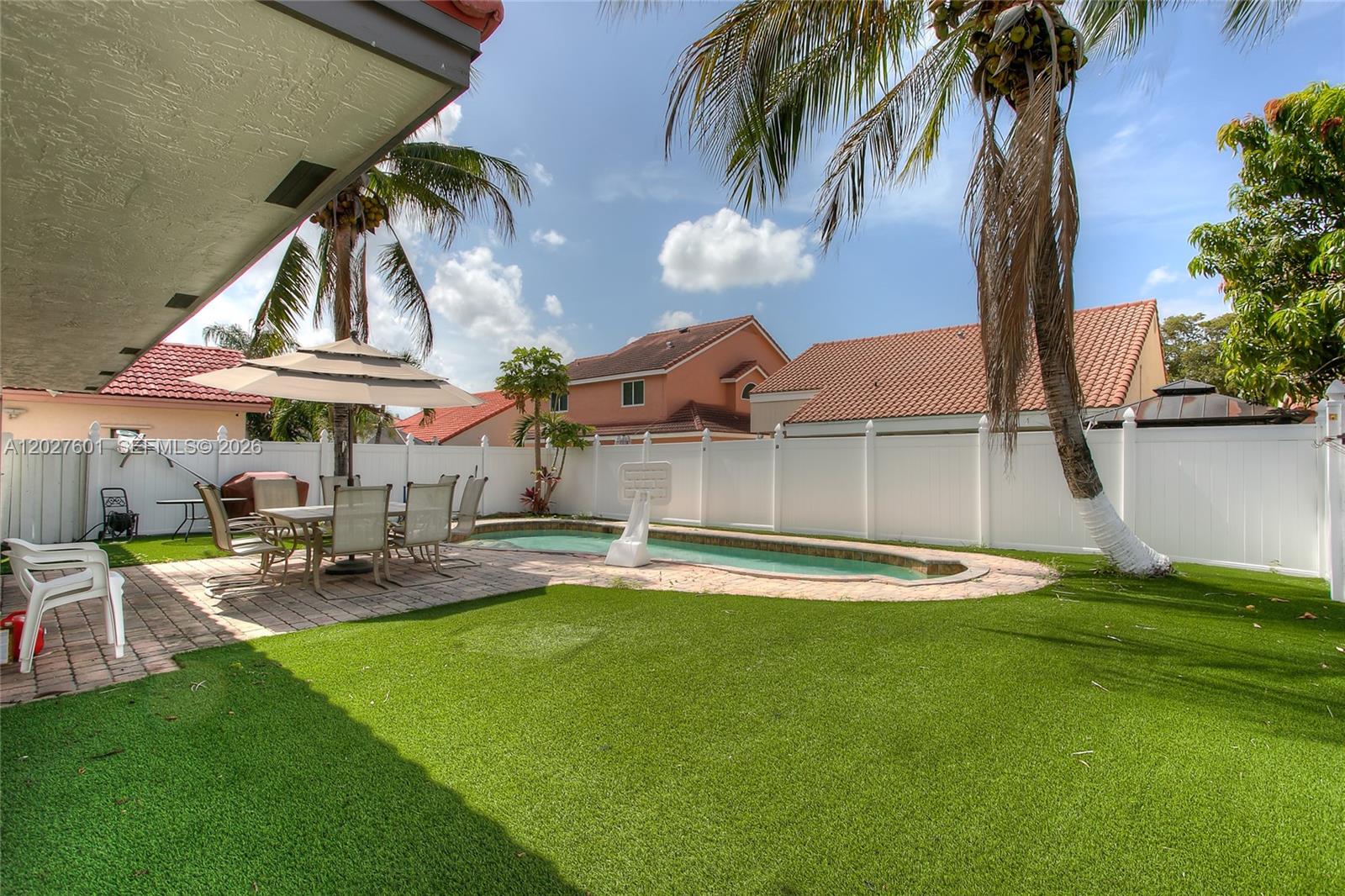 A backyard features a swimming pool, a patio dining set, and artificial turf — 9521 NW 18th Mnr, Plantation FL 33322, PLANTATION, FL