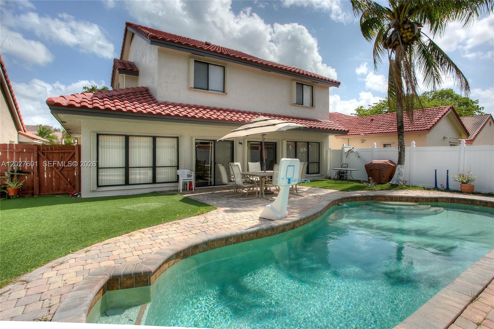 A two-story house with a red tile roof overlooks a backyard pool and patio — 9521 NW 18th Mnr, Plantation FL 33322, PLANTATION, FL