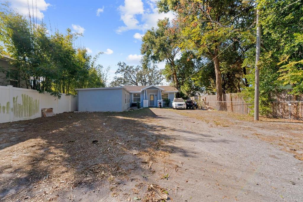 A single-story house with a gravel driveway and a white fence under a blue sky — 4204 N MARGUERITE STREET, TAMPA, FL
