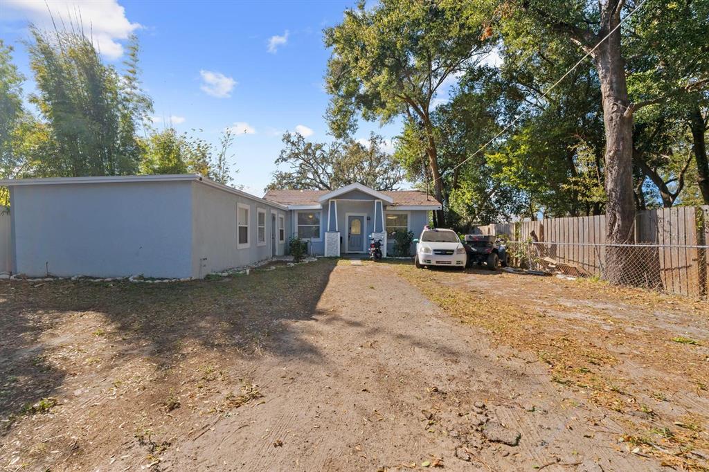 A single-story house with a gray exterior, a dirt driveway, and a wooden fence — 4204 N MARGUERITE STREET, TAMPA, FL