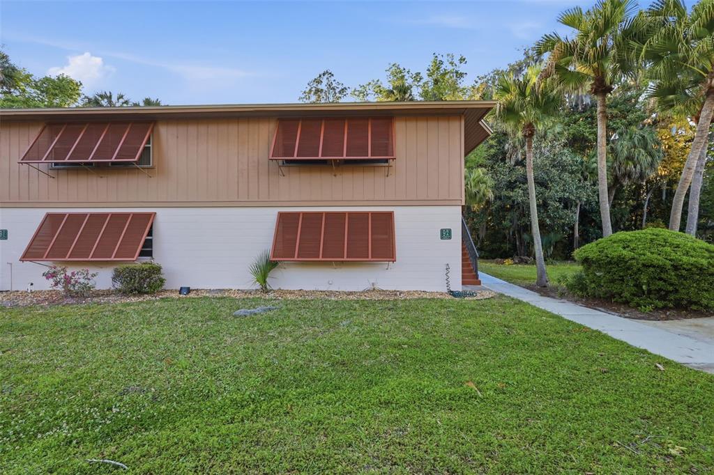A two-story building exterior features tan siding, white stucco, and brown louvered window shutters — 100 SWEETGUM WOODS COURT UNIT 9B, DELTONA, FL