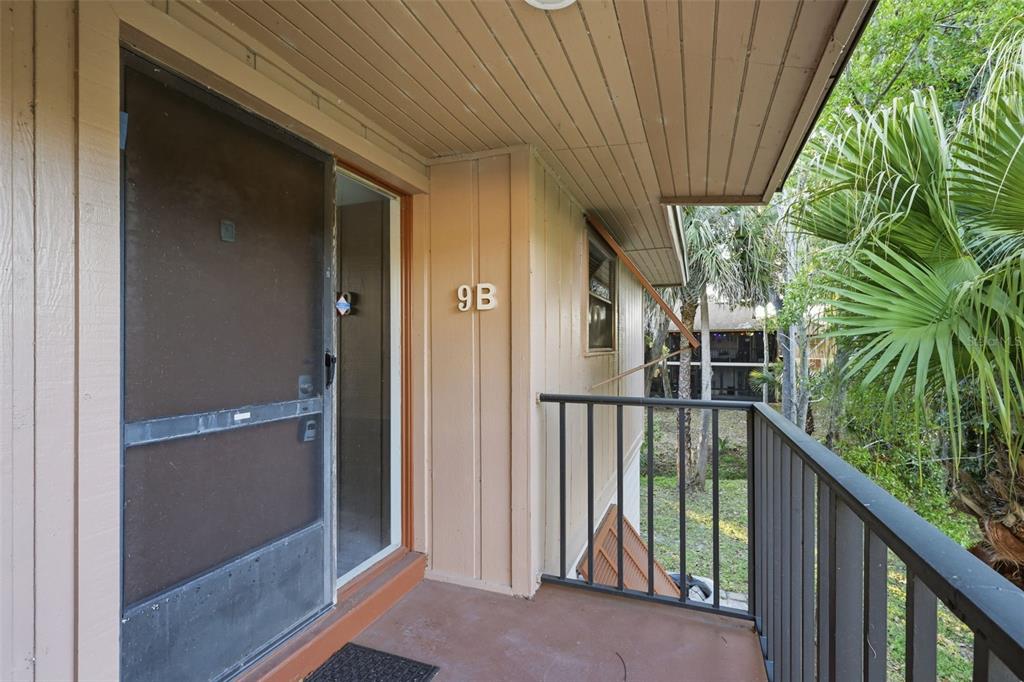 A balcony with a screen door, metal railing, and unit number 9B on the wall — 100 SWEETGUM WOODS COURT UNIT 9B, DELTONA, FL