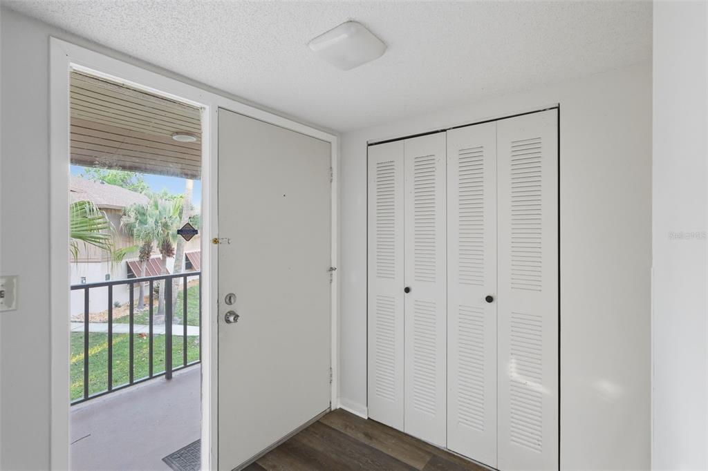 An entryway features a white front door, louvered closet doors, and wood-look flooring — 100 SWEETGUM WOODS COURT UNIT 9B, DELTONA, FL