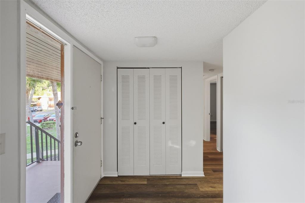 An entryway features a white front door, a louvered closet, and dark wood-look flooring — 100 SWEETGUM WOODS COURT UNIT 9B, DELTONA, FL